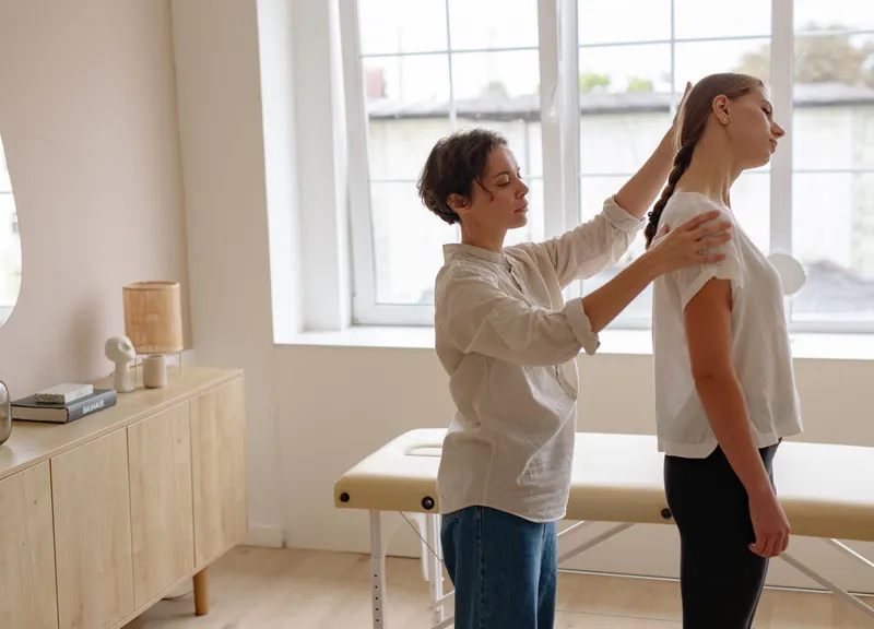Practitioner checking a young woman’s standing posture