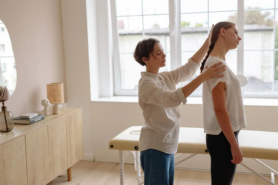 Practitioner checking a young woman’s standing posture