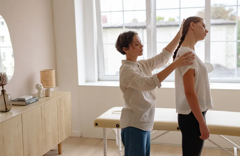 Practitioner checking a young woman’s standing posture