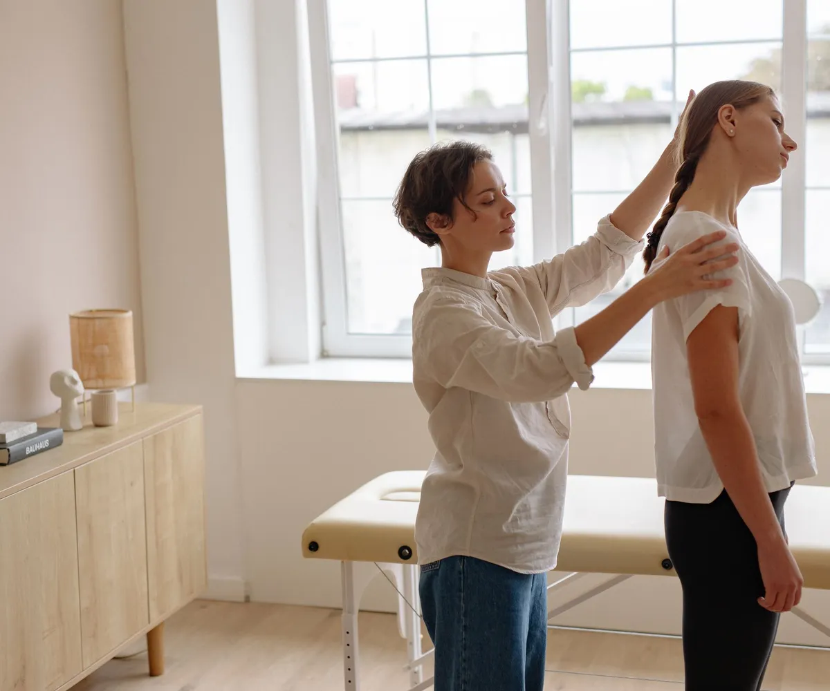 Practitioner checking a young woman’s standing posture