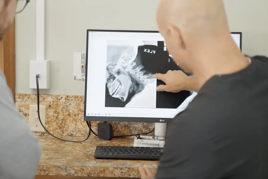 Dr. Woodbury reviewing a neck X-ray on screen with a patient