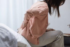 Woman sitting on the couch holding back