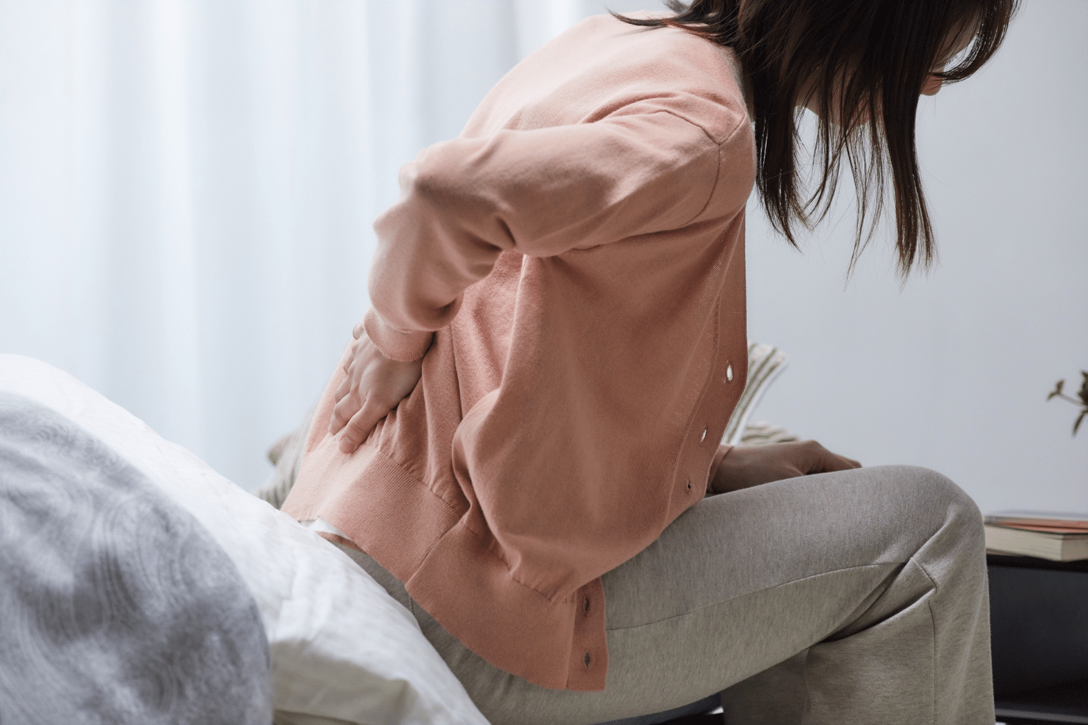 Woman sitting on the couch holding back